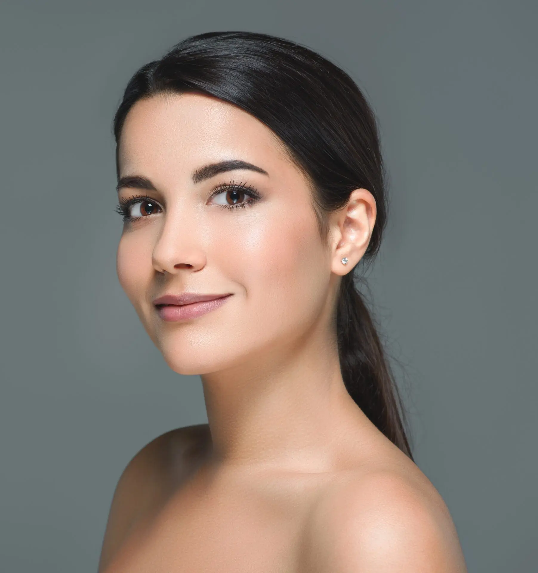 Junge Frau mit natürlichem Make-up, neutraler Hintergrund.
